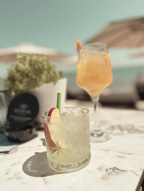 Two cocktails with fresh fruit on a marble table at OKKIO