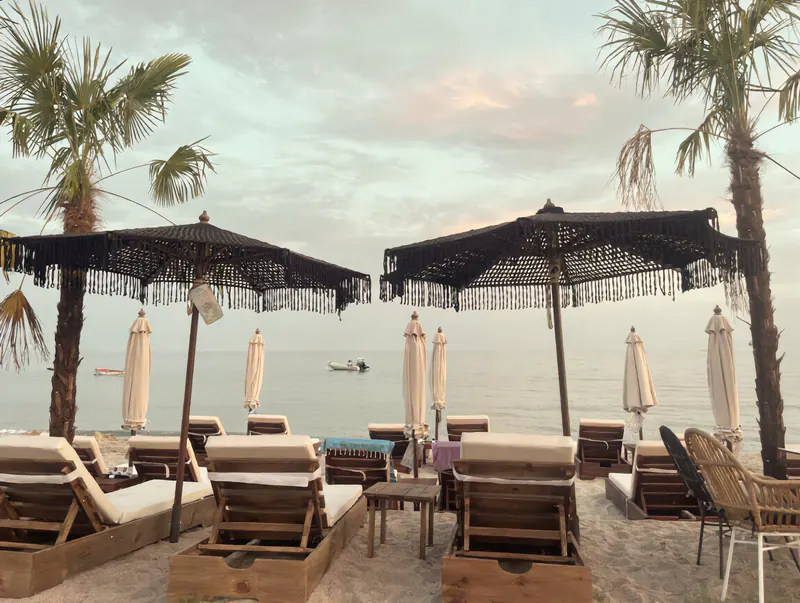 Sunbeds under fringed parasols facing the sea at OKKIO