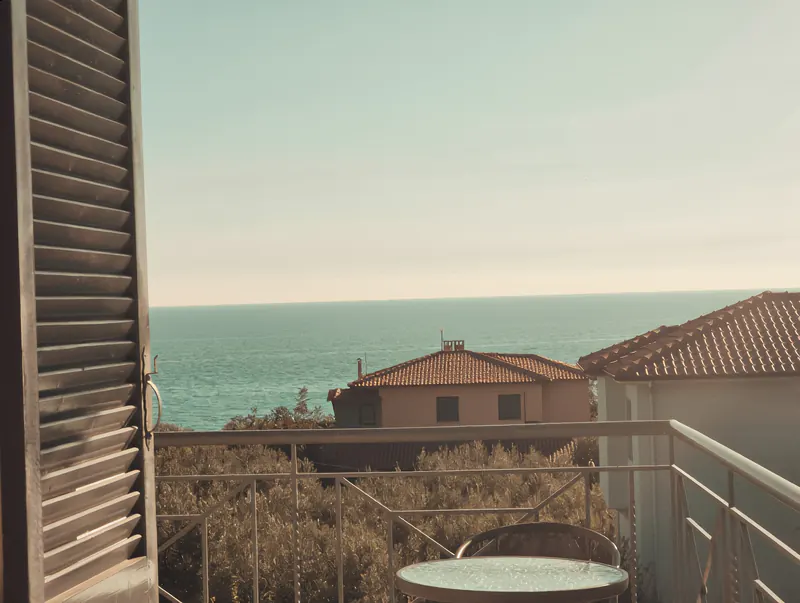 Sea view over rooftops and olive trees from a Theros Apartments balcony